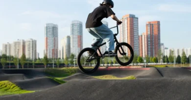 Велосипедист в шлеме выполняет прыжок на BMX на открытой площадке