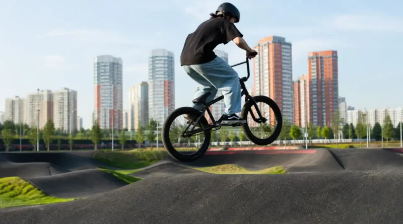 Велосипедист в шлеме выполняет прыжок на BMX на открытой площадке