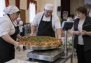 Повара и специалист проверяют большой пирог на весах перед фиксацией результата